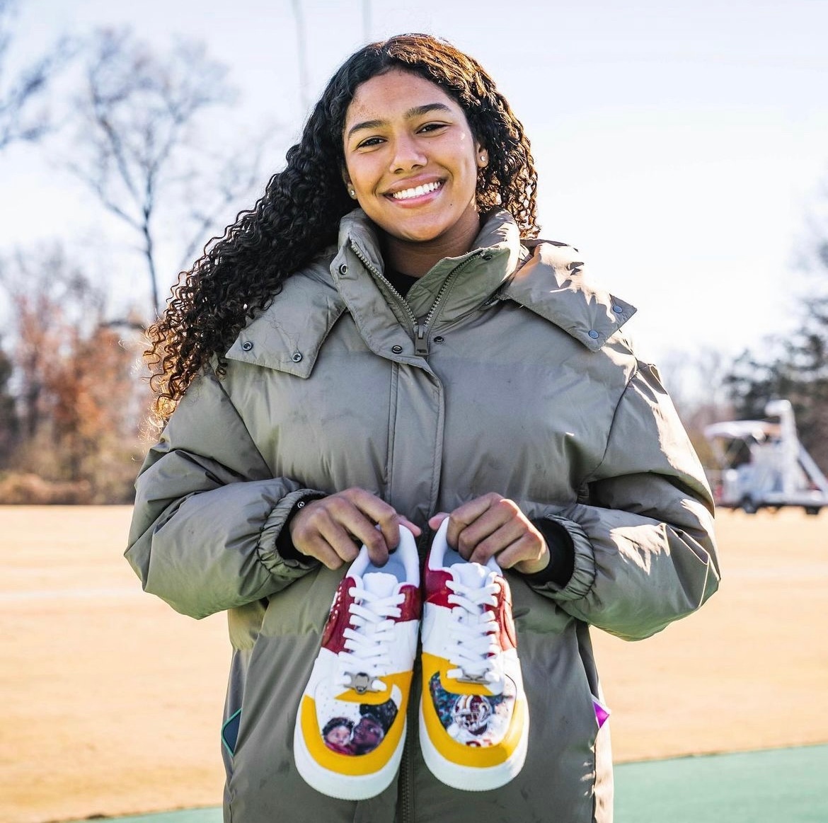 Photo of Jackie Taylor with a pair of custom shoes at a Washington Commanders practice.